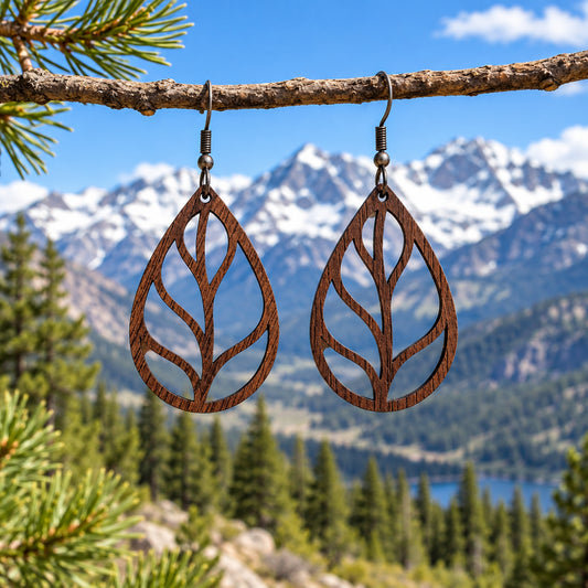 A pair of dark brown walnut wood teardrop dangle earrings with a leaf cutout design, hanging from bronze-toned fishhook wires.